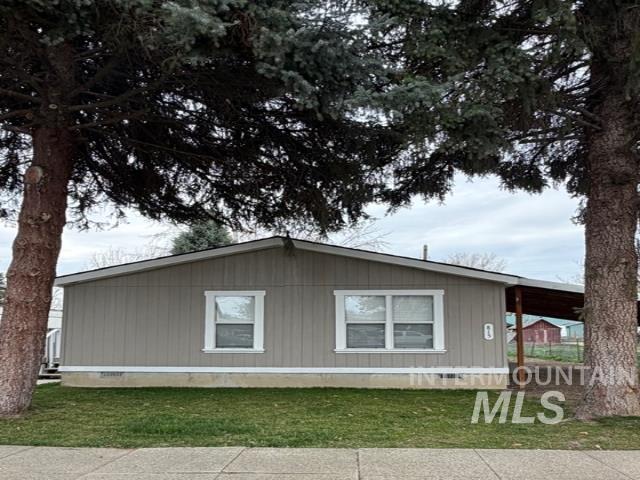 View of side of home with crawl space, a lawn, and a carport