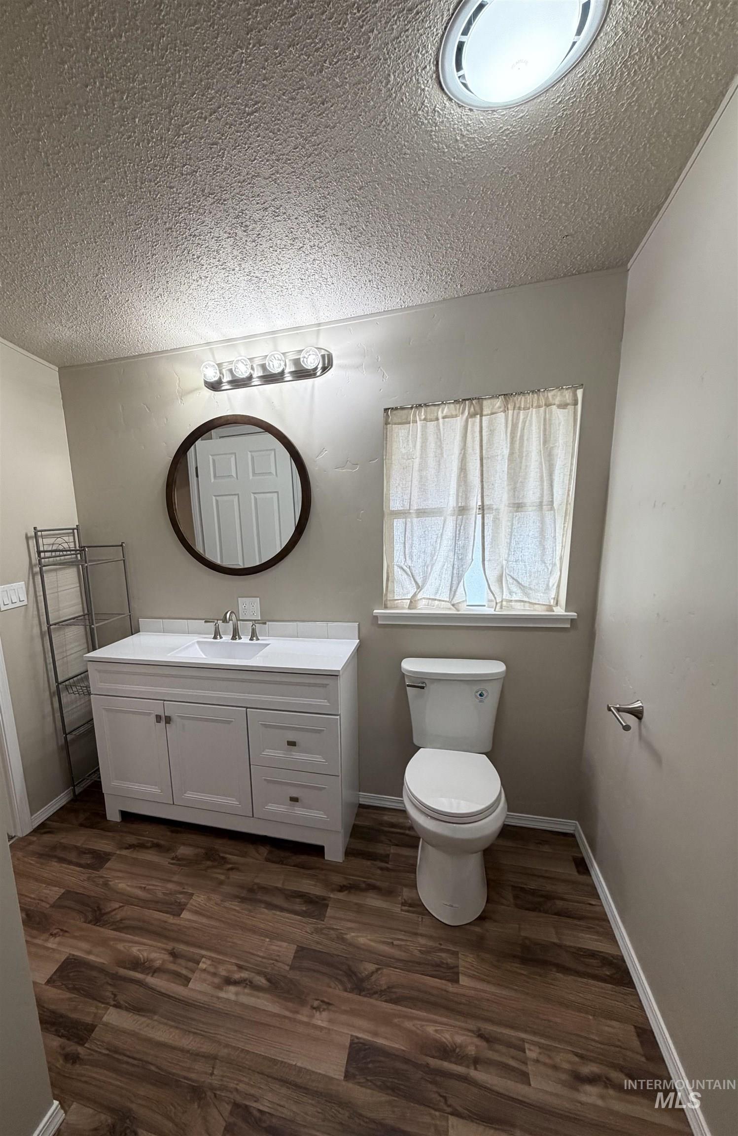 Bathroom with vanity, dark wood-style flooring, and a textured ceiling