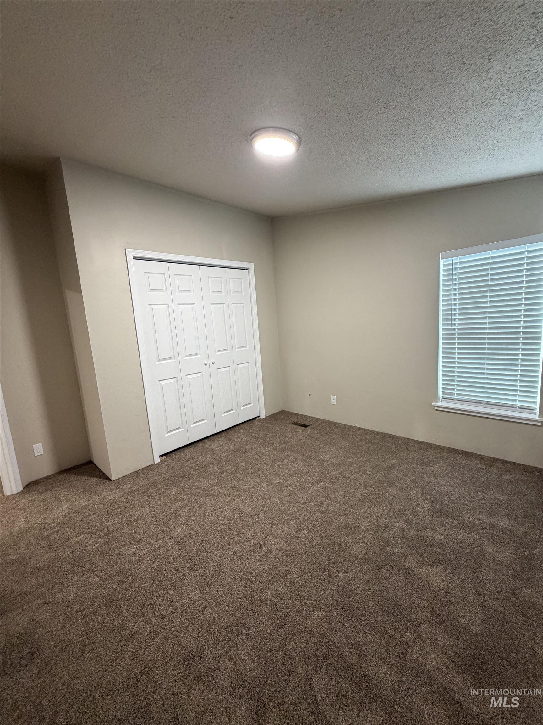 Unfurnished bedroom with carpet floors, a textured ceiling, and a closet