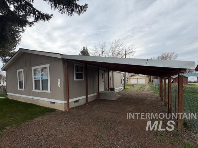 View of side of home with crawl space, a carport, and dirt driveway