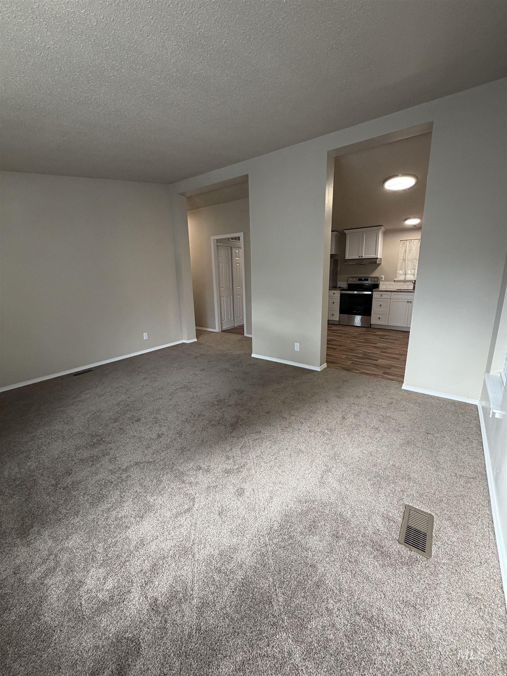 Unfurnished living room with light carpet and a textured ceiling