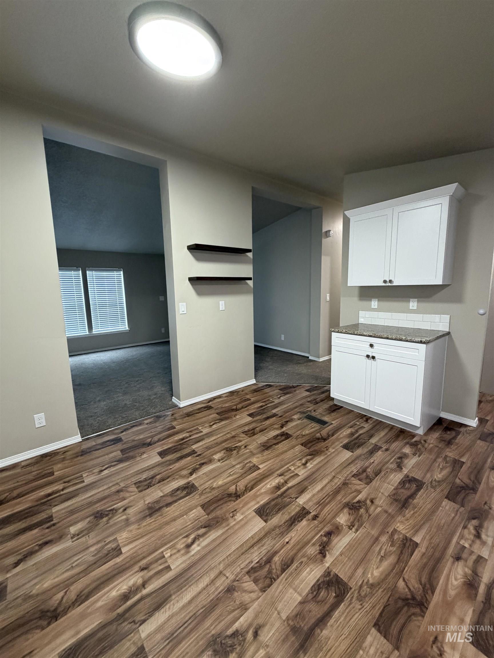 Kitchen with white cabinets, dark stone countertops, and dark wood-style floors