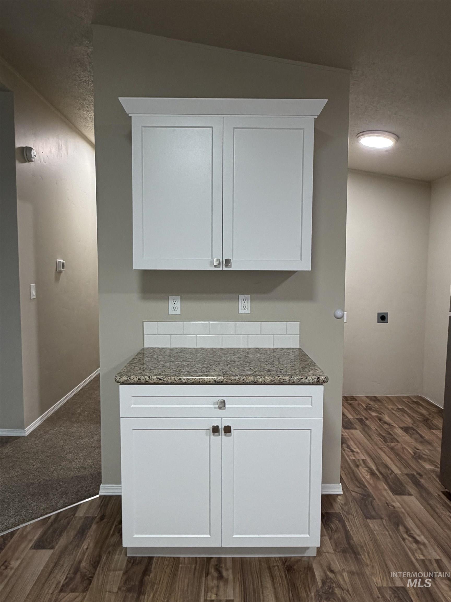 Kitchen featuring dark stone counters, dark wood-style floors, white cabinets, and a textured ceiling