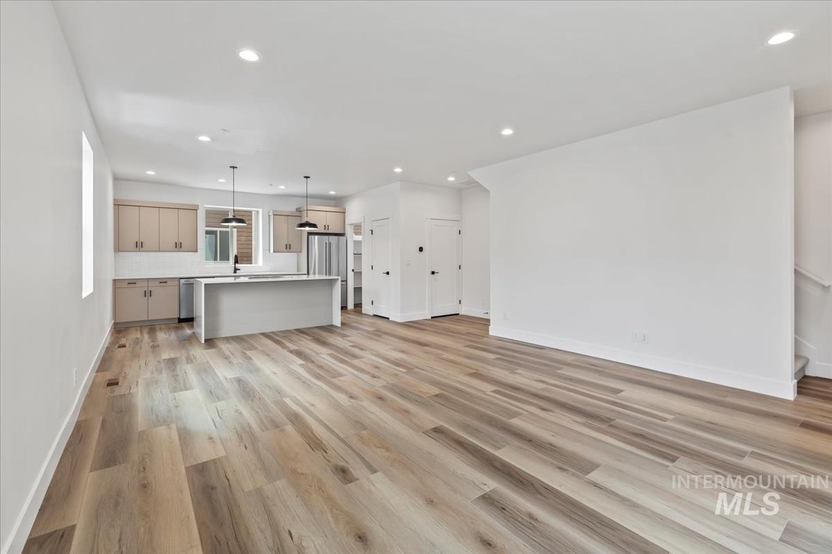 Unfurnished living room with recessed lighting, light wood finished floors, and stairway