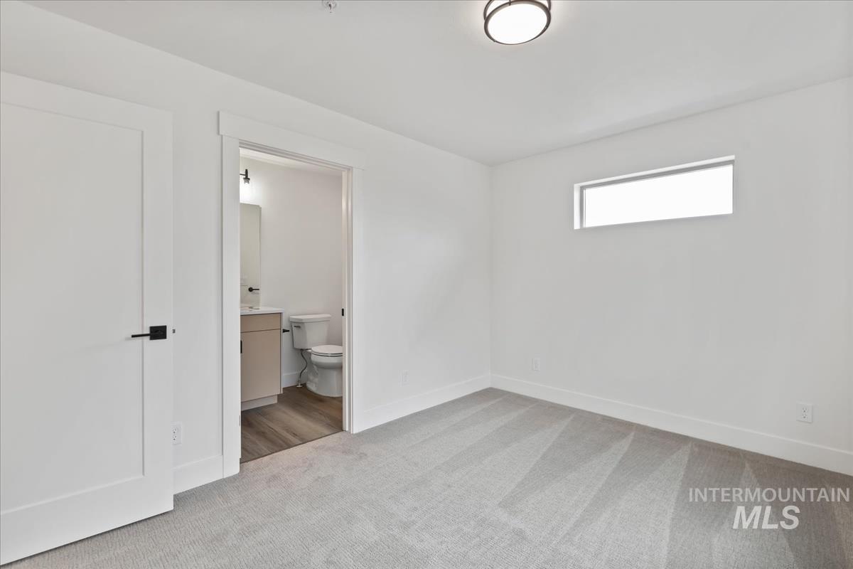 Unfurnished bedroom with light carpet and ensuite bath