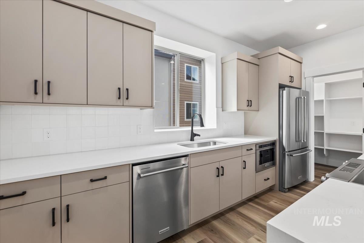 Kitchen featuring stainless steel appliances, dark wood finished floors, backsplash, open shelves, and light stone countertops