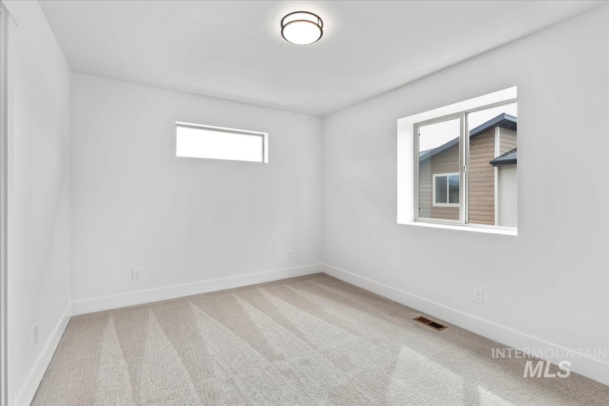 Empty room featuring light carpet and baseboards