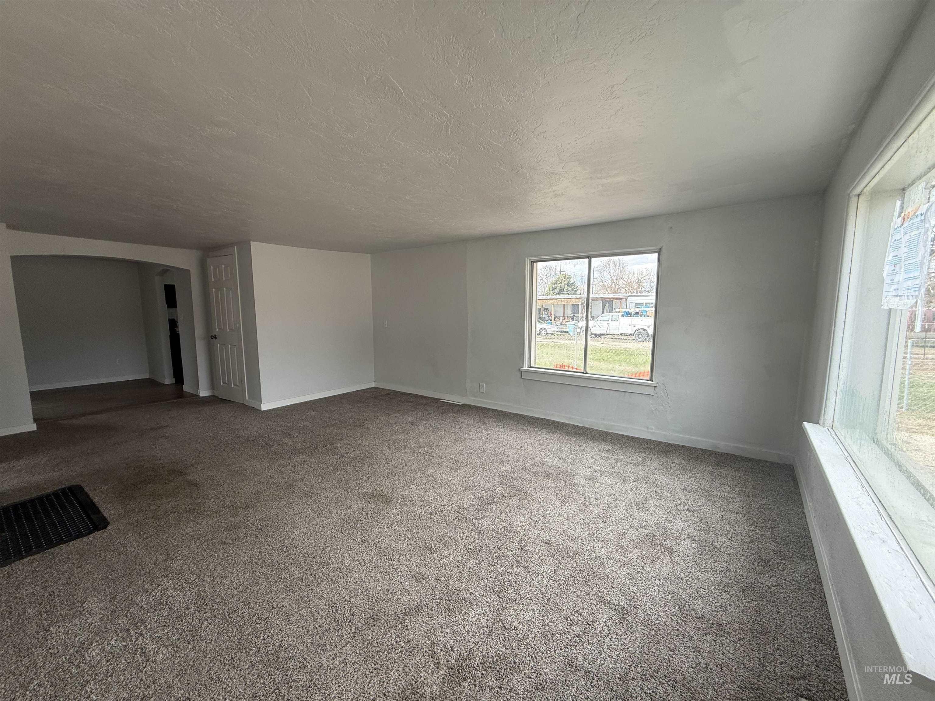 Spare room featuring carpet, a textured ceiling, and arched walkways