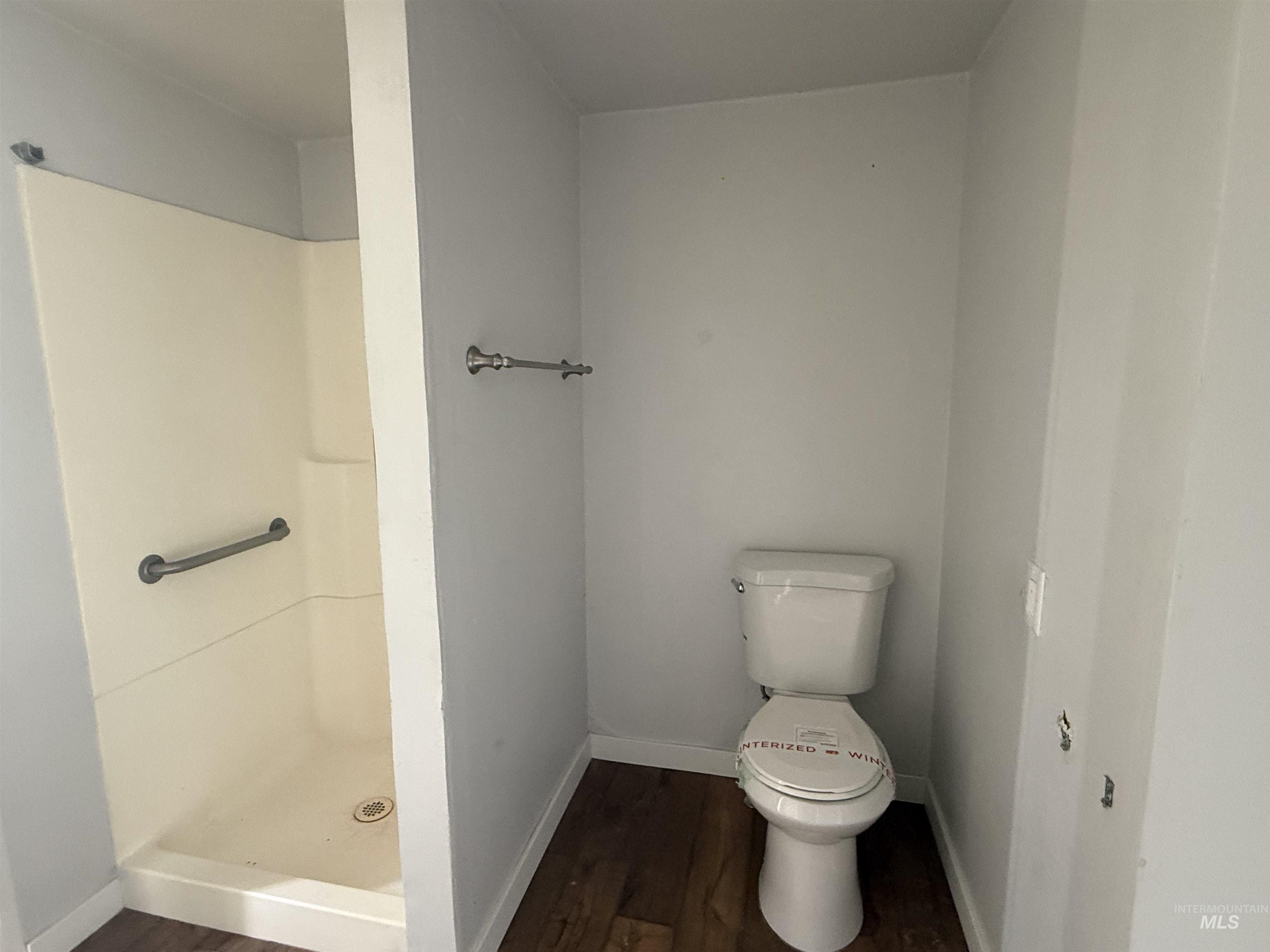 Bathroom with a stall shower and dark wood-type flooring