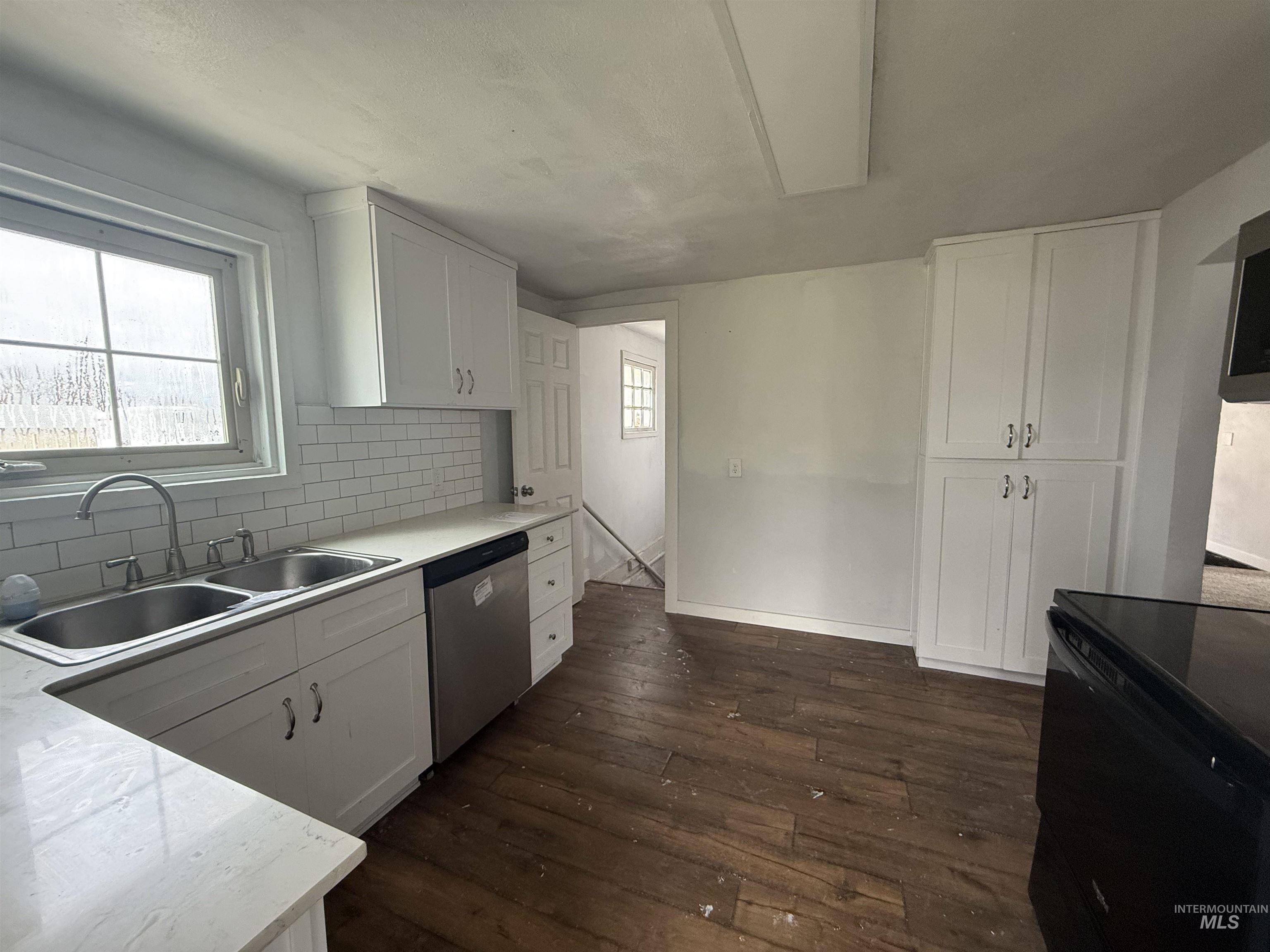 Kitchen with white cabinets, tasteful backsplash, stainless steel appliances, and dark wood-type flooring