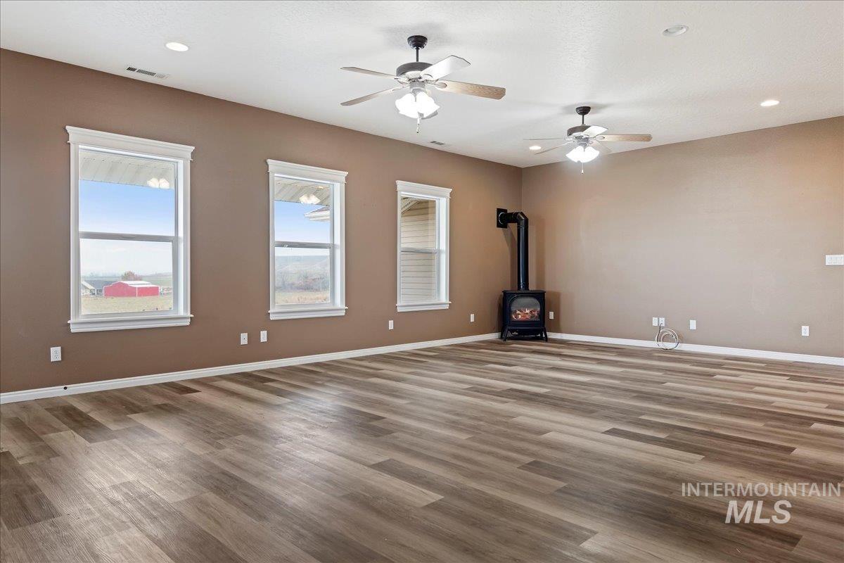 Unfurnished living room with a wood stove, light wood-type flooring, recessed lighting, and a ceiling fan