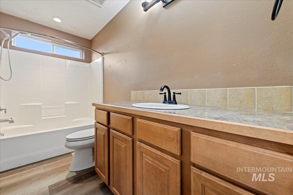 Full bathroom featuring vanity, shower / washtub combination, dark wood-style flooring, a textured ceiling, and a textured wall