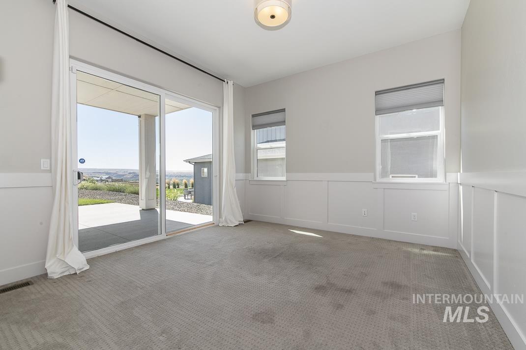 Spare room featuring healthy amount of natural light, carpet, a decorative wall, and a wainscoted wall