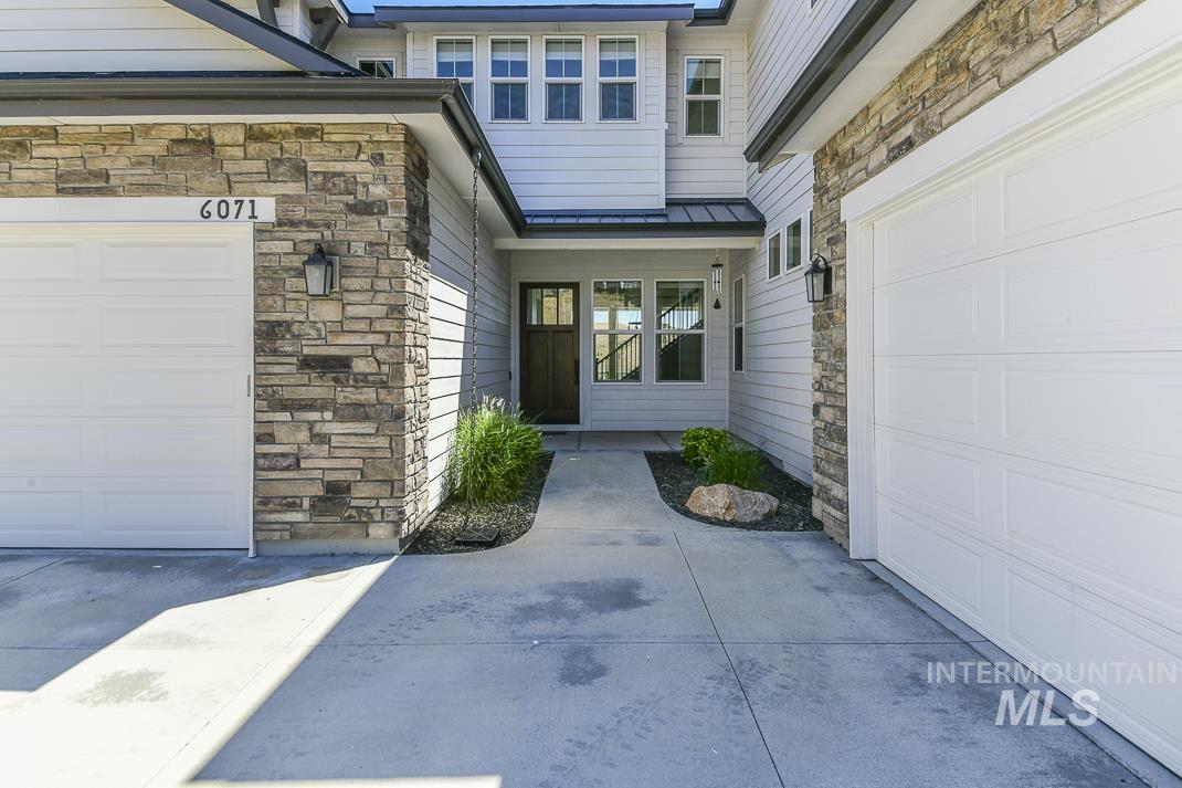 View of exterior entry featuring stone siding, a standing seam roof, a metal roof, and concrete driveway