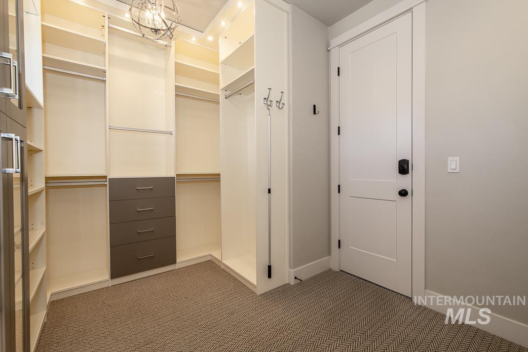 Spacious closet with carpet floors and a chandelier