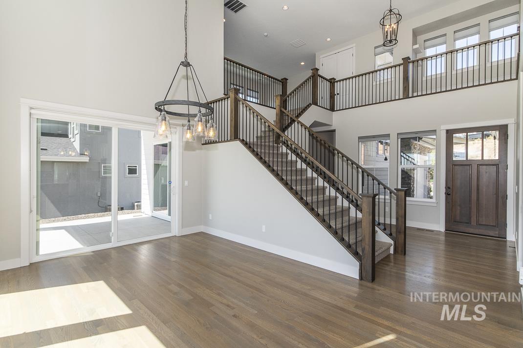 Entrance foyer featuring a chandelier, a high ceiling, wood finished floors, recessed lighting, and stairs
