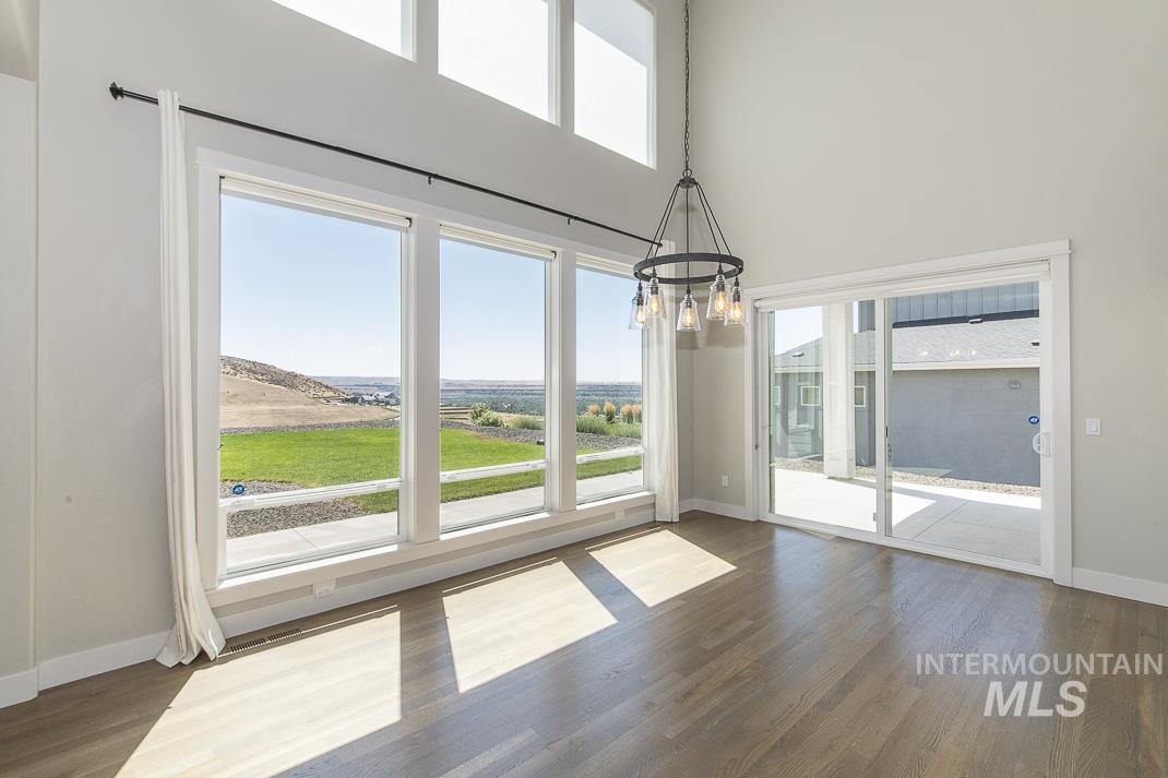 Unfurnished dining area with a high ceiling, a chandelier, and wood finished floors