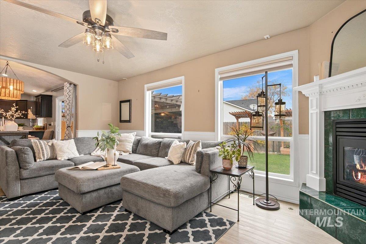 Living room with a fireplace, a wainscoted wall, arched walkways, wood finished floors, and a textured ceiling