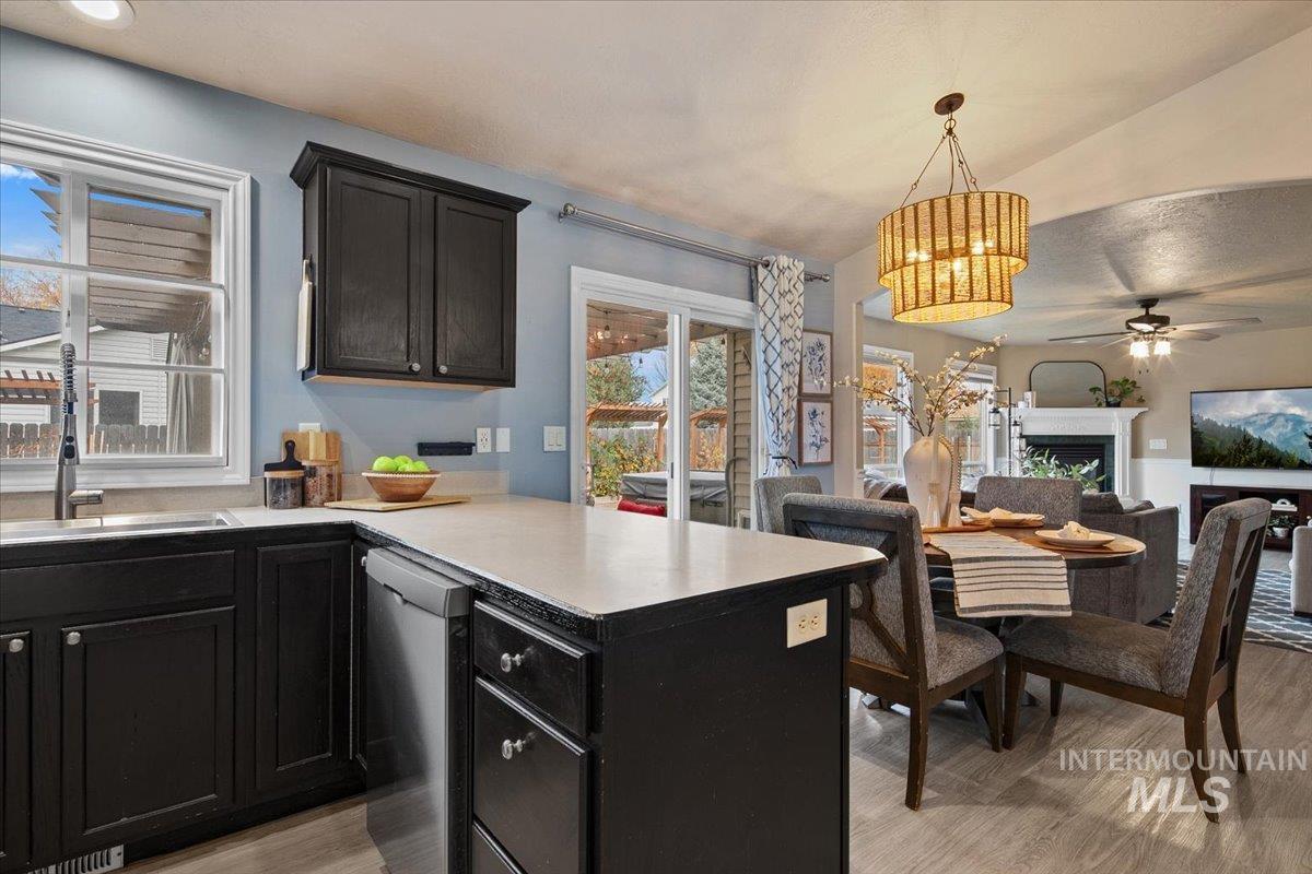 Kitchen with a fireplace, dark cabinetry, a peninsula, and stainless steel dishwasher
