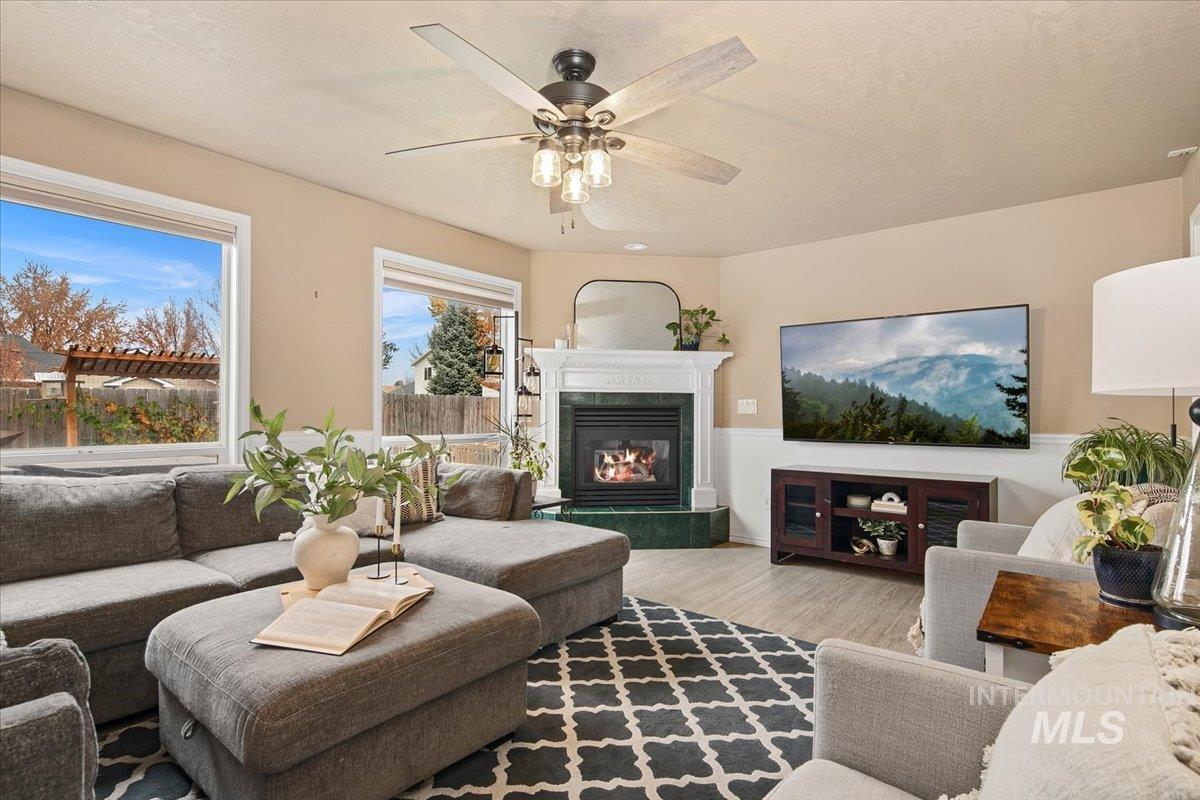Living area featuring a fireplace, light wood-style flooring, a textured ceiling, and ceiling fan