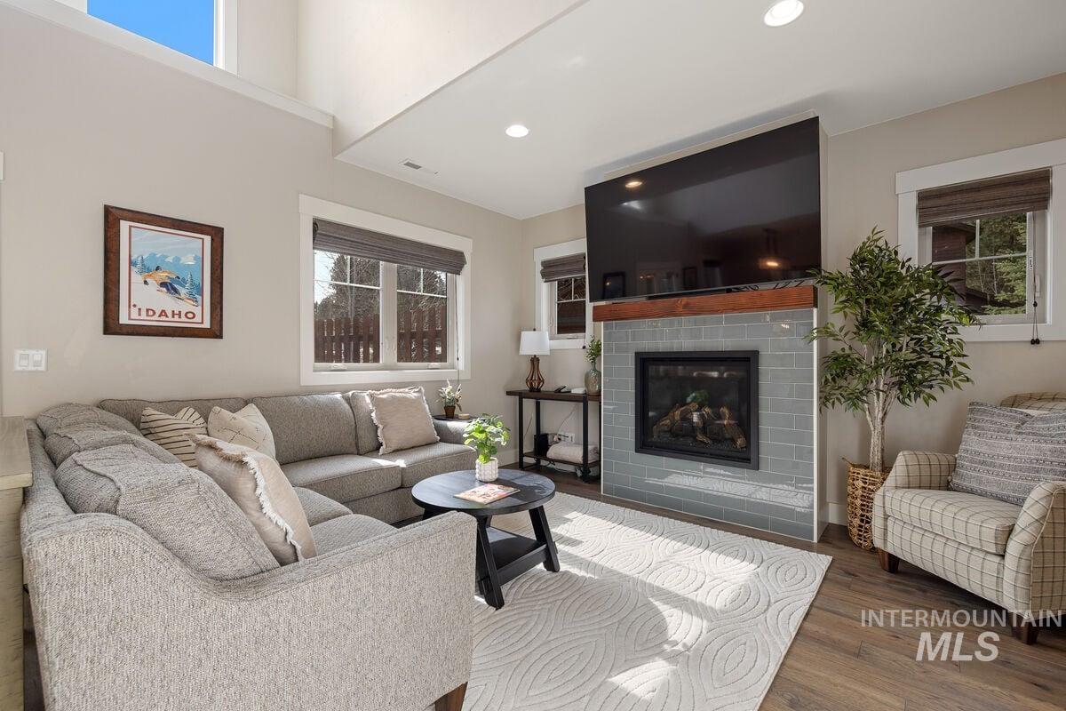 Living area featuring a glass covered fireplace, wood finished floors, and recessed lighting