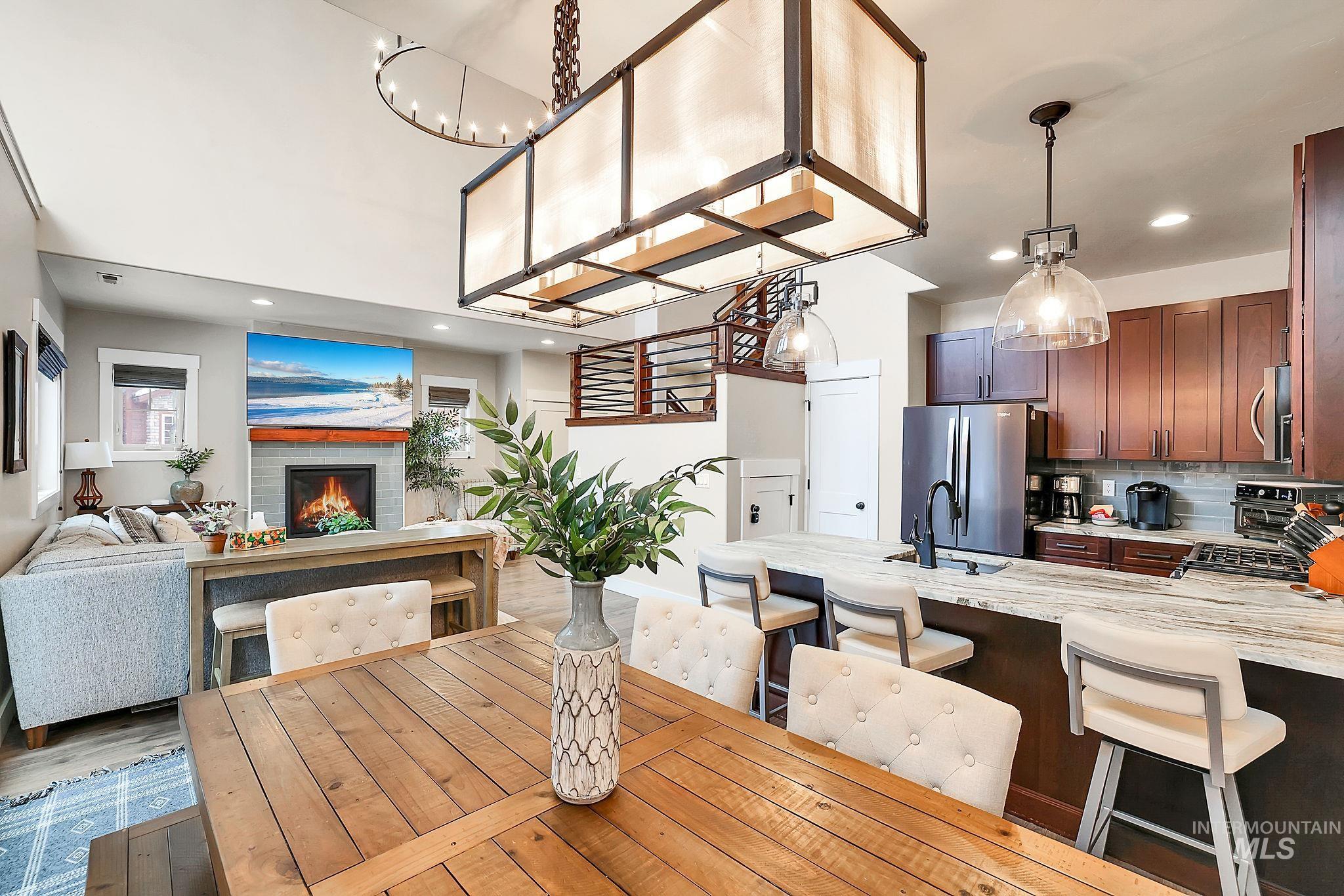 Dining room featuring a warm lit fireplace, recessed lighting, and light wood-type flooring