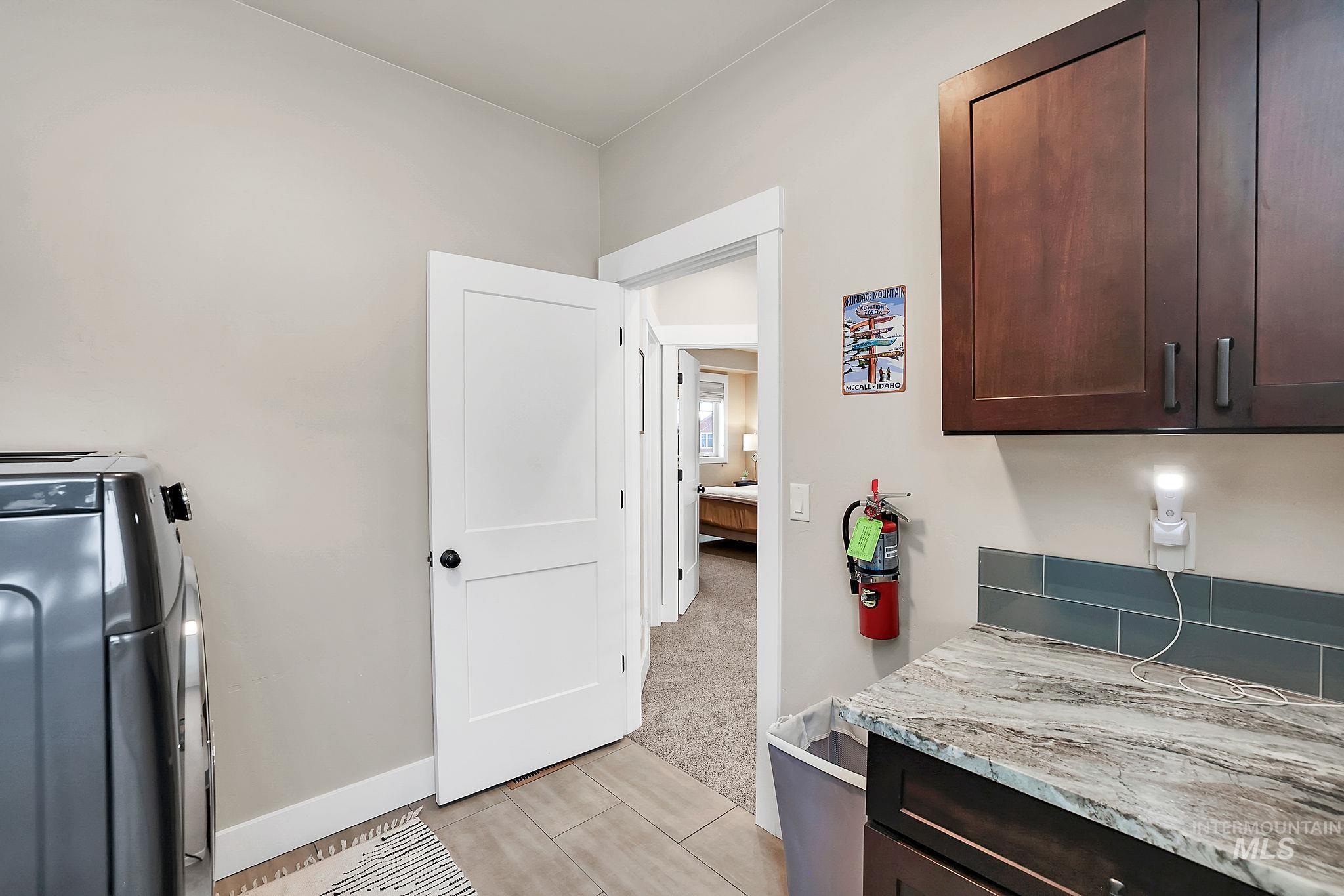 Laundry room with washer / clothes dryer, light carpet, and light tile patterned floors