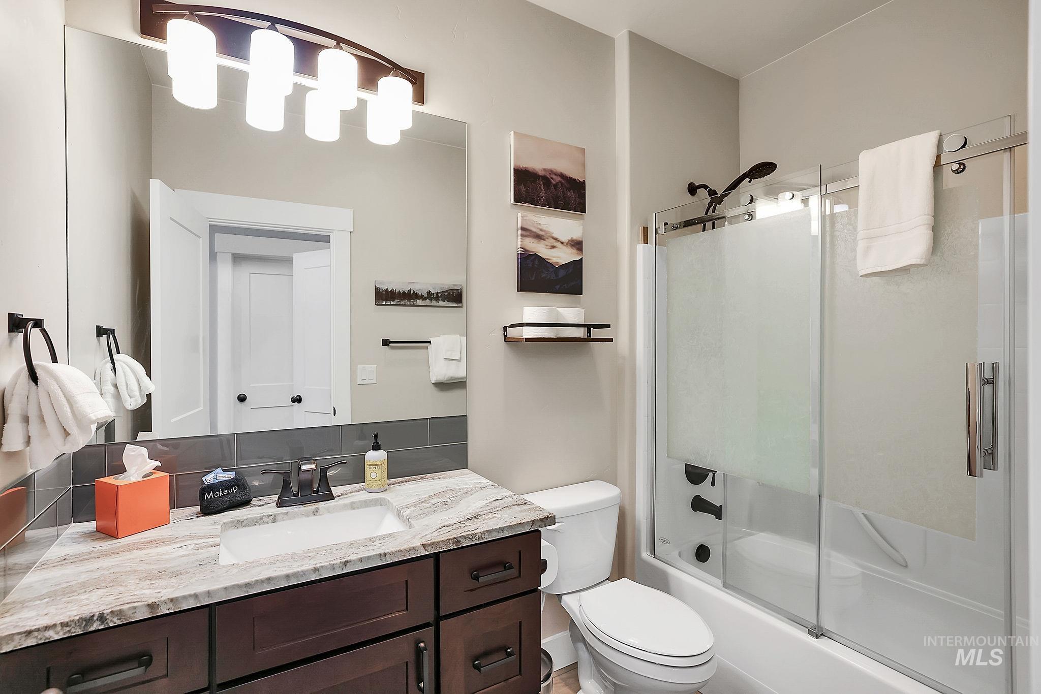 Full bathroom featuring vanity, bath / shower combo with glass door, and decorative backsplash