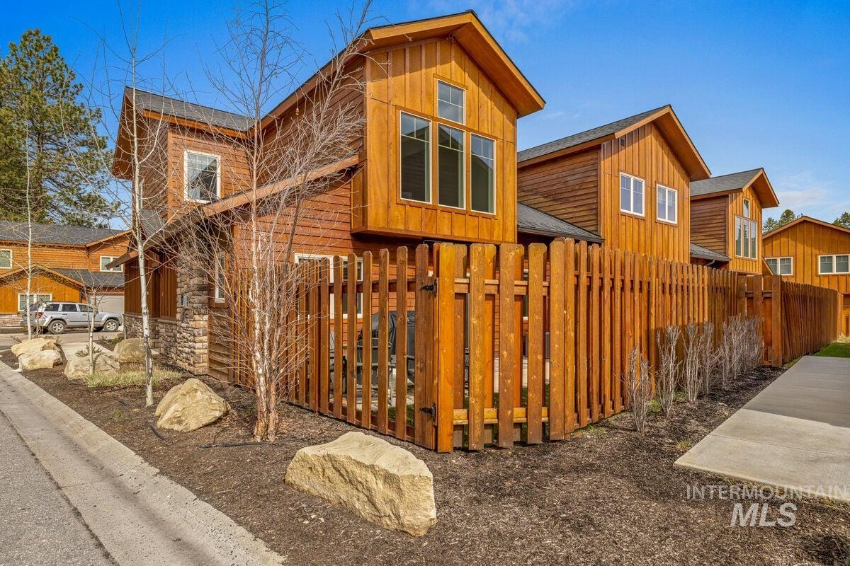 View of property exterior with board and batten siding, a fenced front yard, and a shingled roof