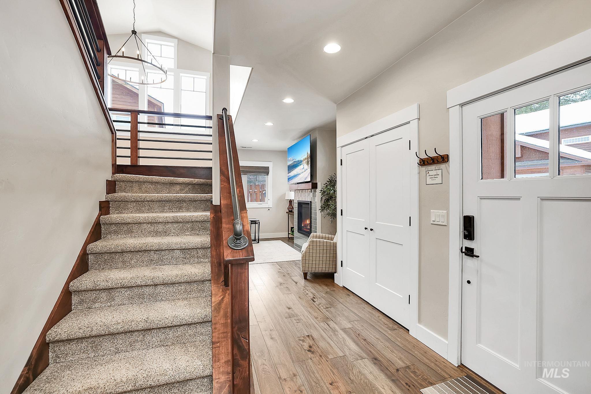 Entrance foyer featuring light wood-type flooring, a warm lit fireplace, and suspended lighting