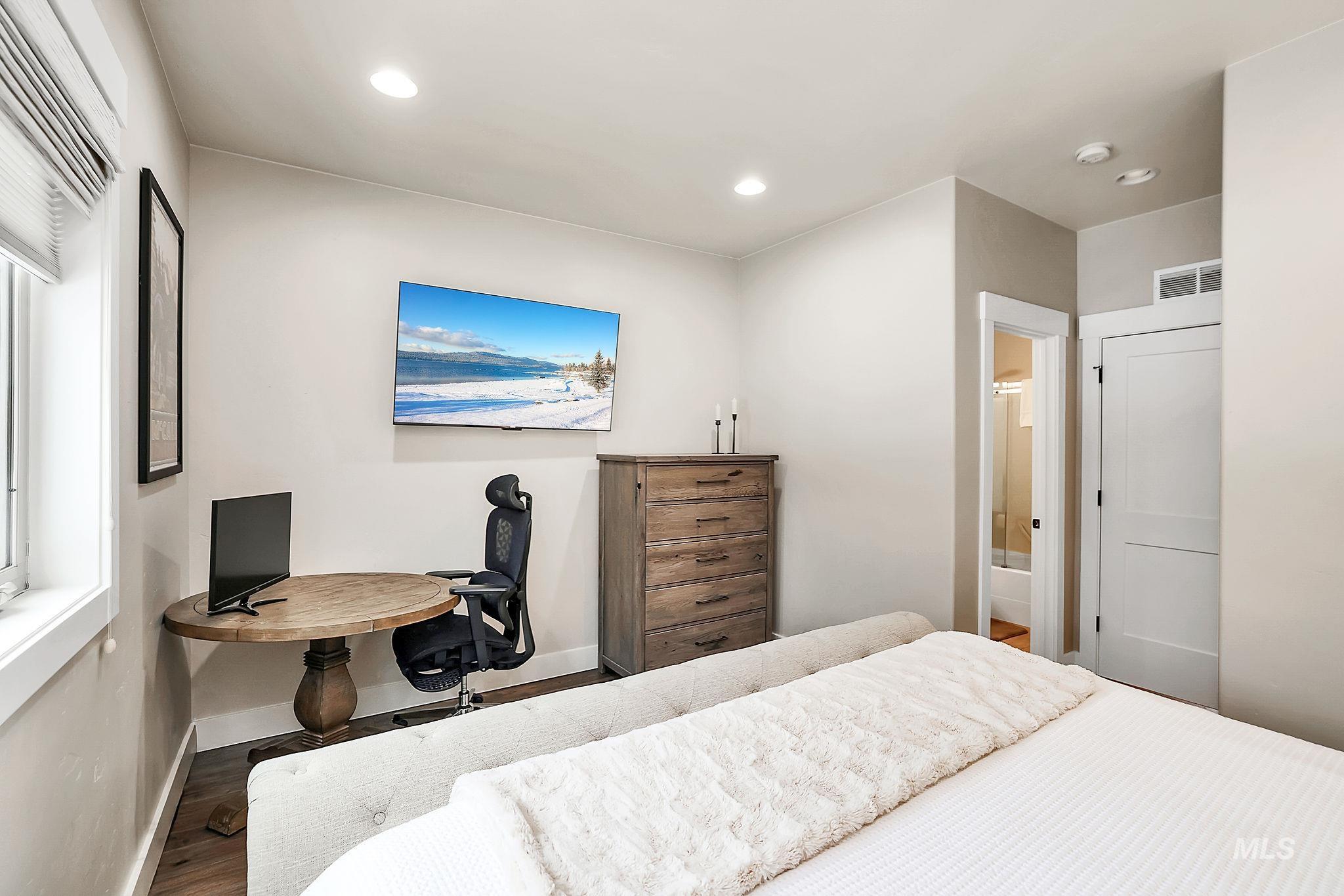 Bedroom featuring wood finished floors, recessed lighting, and connected bathroom
