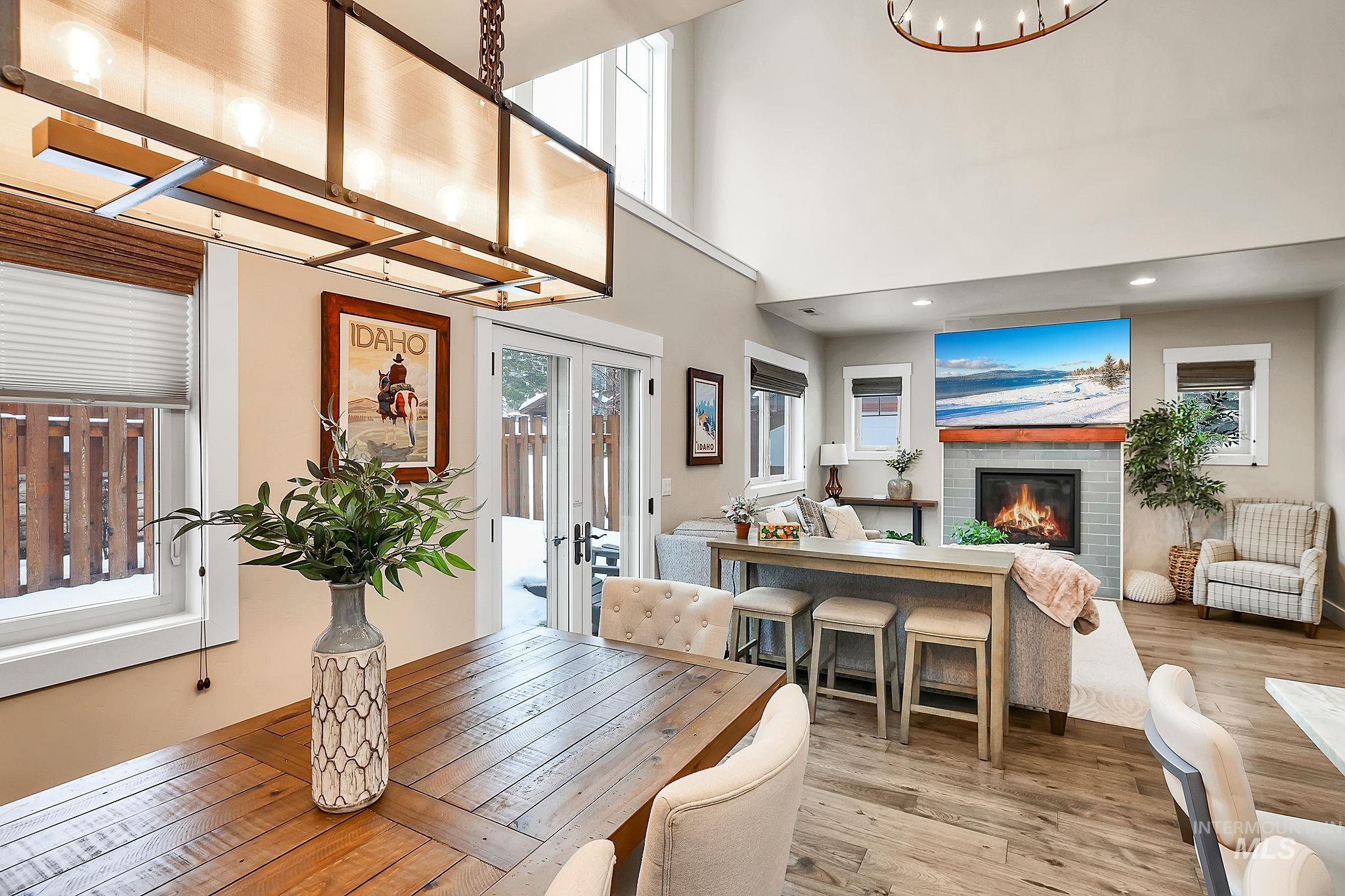 Dining room with a glass covered fireplace, a high ceiling, wood finished floors, french doors, and recessed lighting