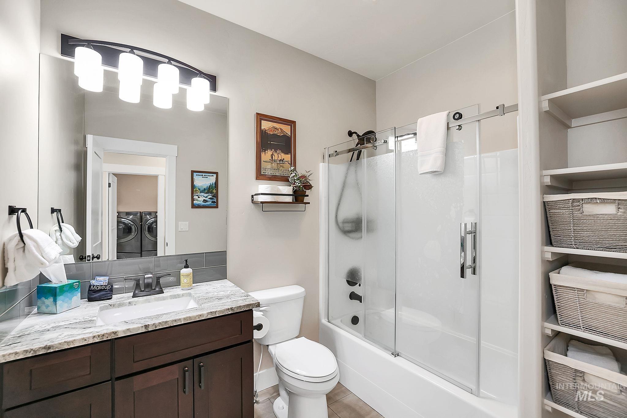 Full bath featuring vanity, washing machine and clothes dryer, and shower / bath combination with glass door