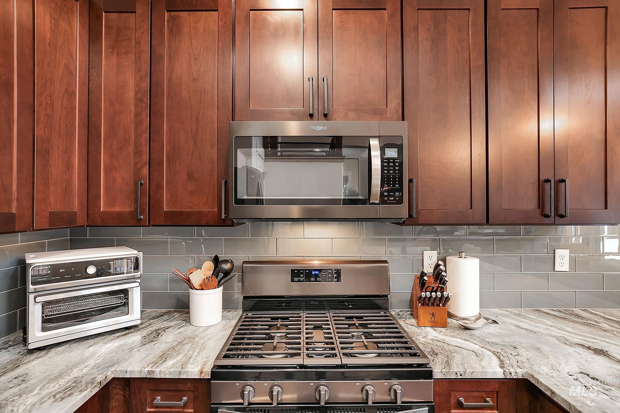 Kitchen with stainless steel appliances, light stone countertops, and tasteful backsplash