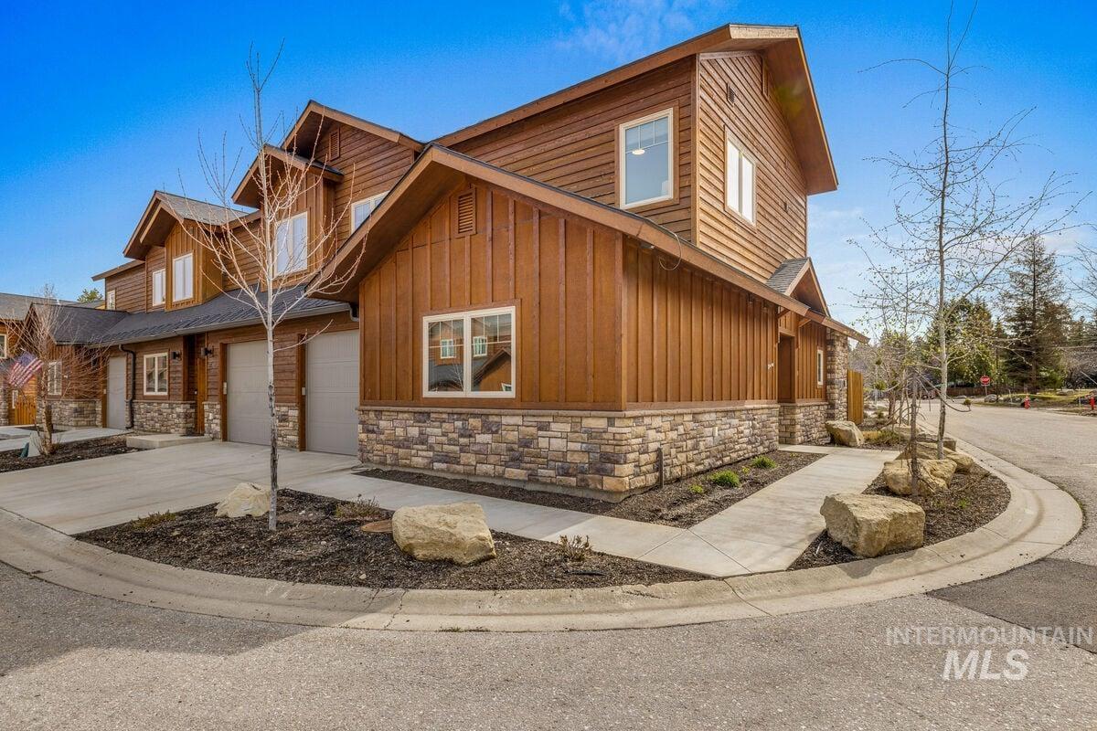View of side of home featuring stone siding, board and batten siding, and driveway