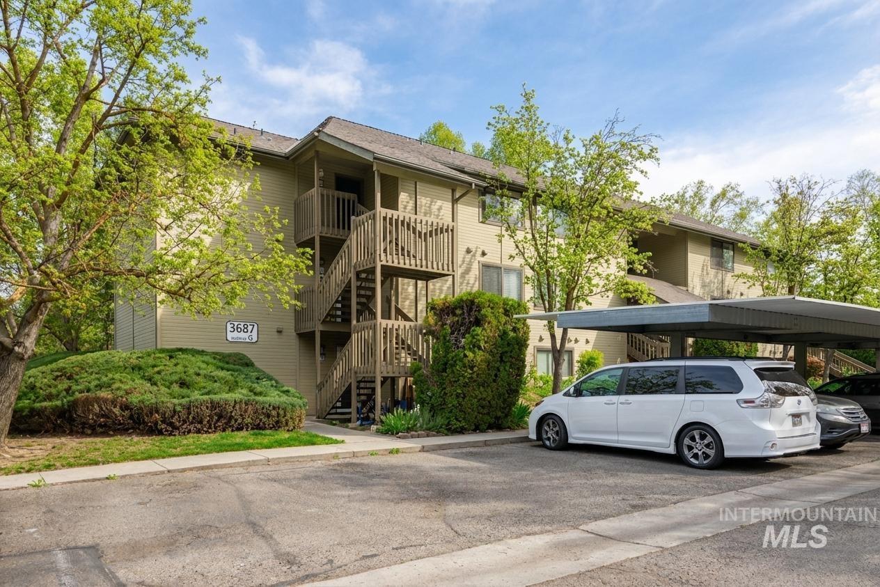 View of apartment building / complex featuring stairway and covered parking