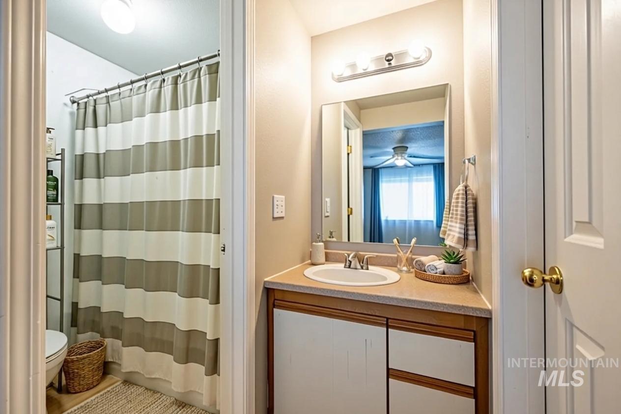 Bathroom with vanity, curtained shower, and a ceiling fan
