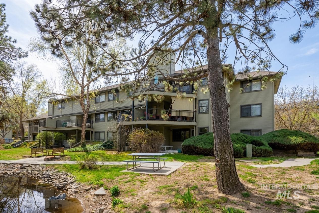 Rear view of property featuring a balcony, a water view, a chimney, and a patio