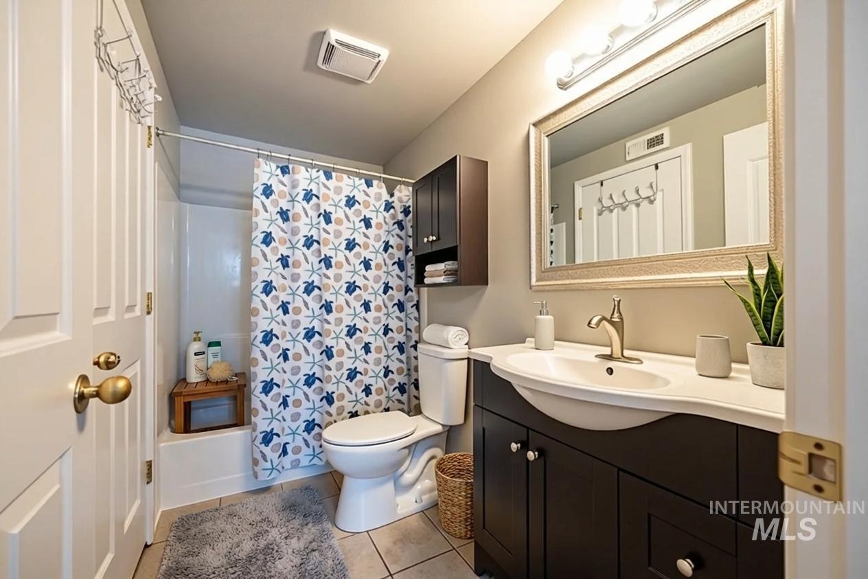 Bathroom featuring vanity, shower / bath combo with shower curtain, and light tile patterned floors