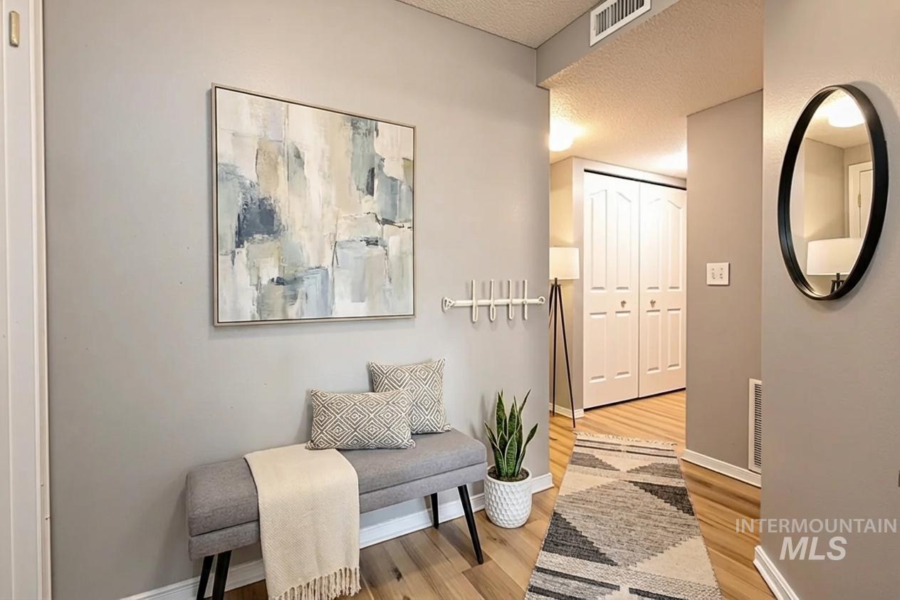 Hallway featuring light wood-type flooring and a textured ceiling
