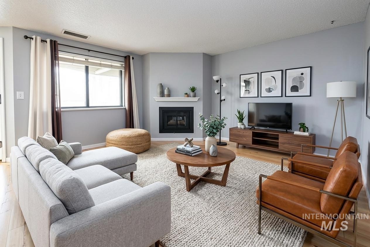 Living room with wood finished floors, a glass covered fireplace, and a textured ceiling