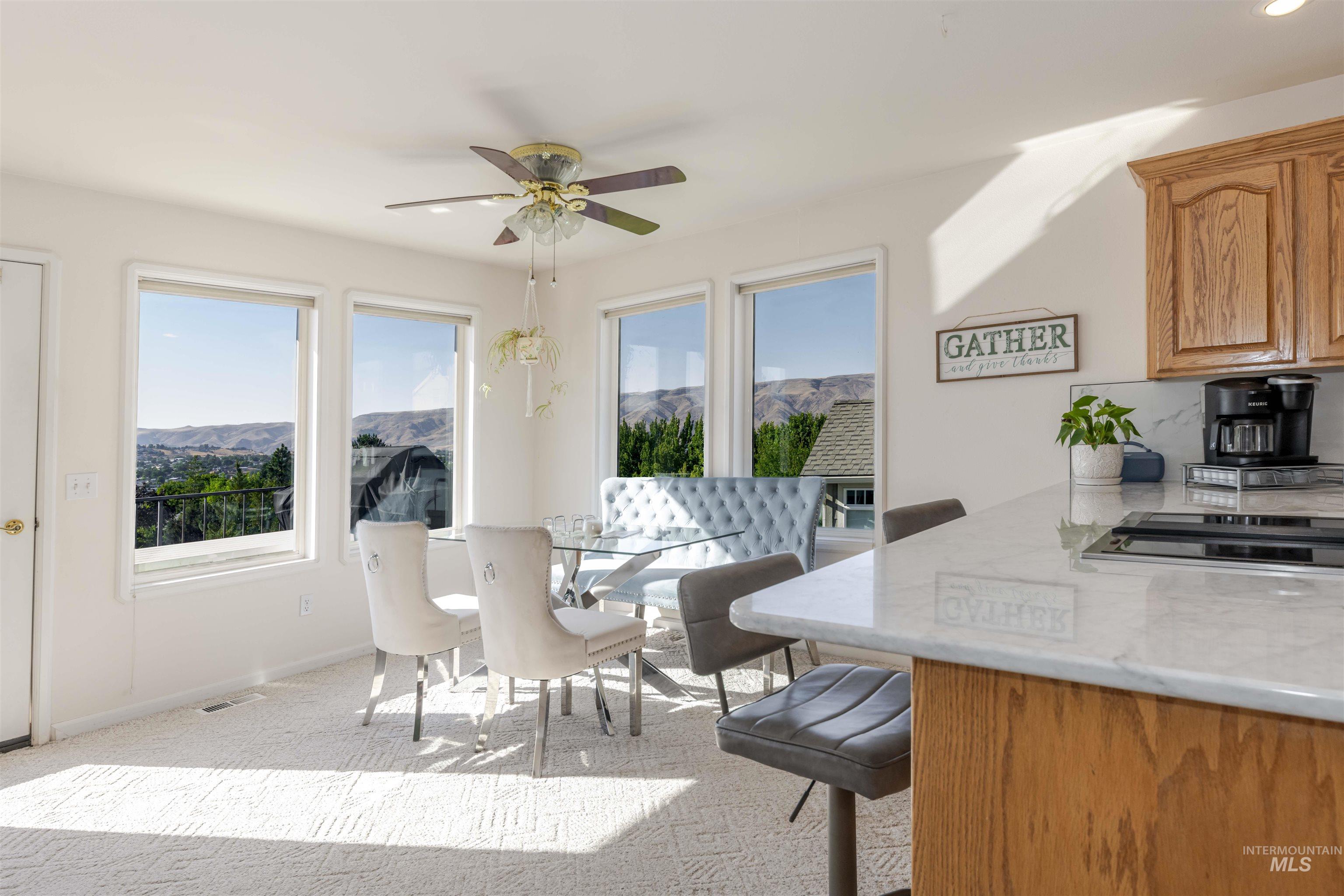 Dining room featuring a mountain view, light carpet, and a ceiling fan