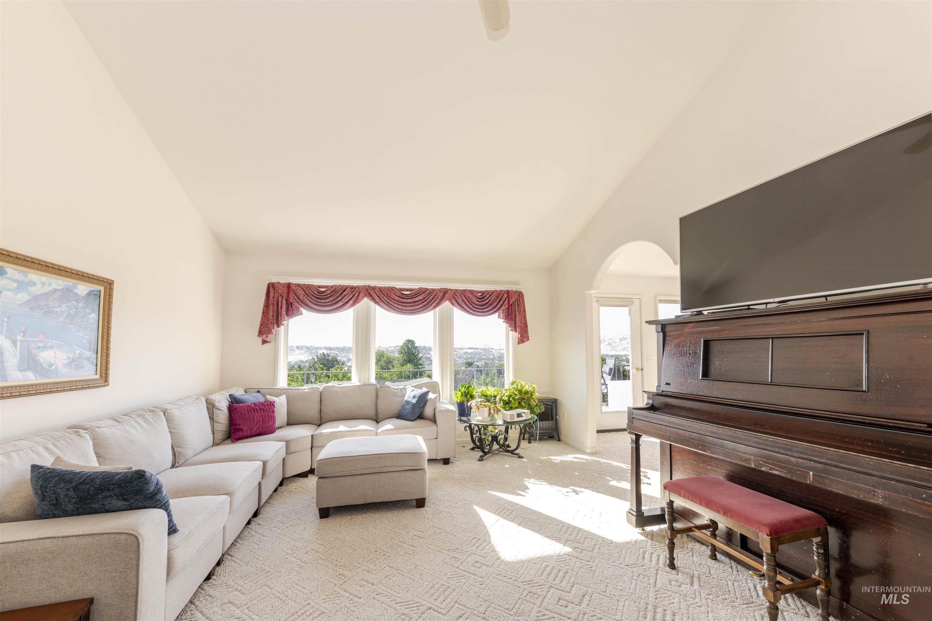 Living room with carpet, high vaulted ceiling, and arched walkways