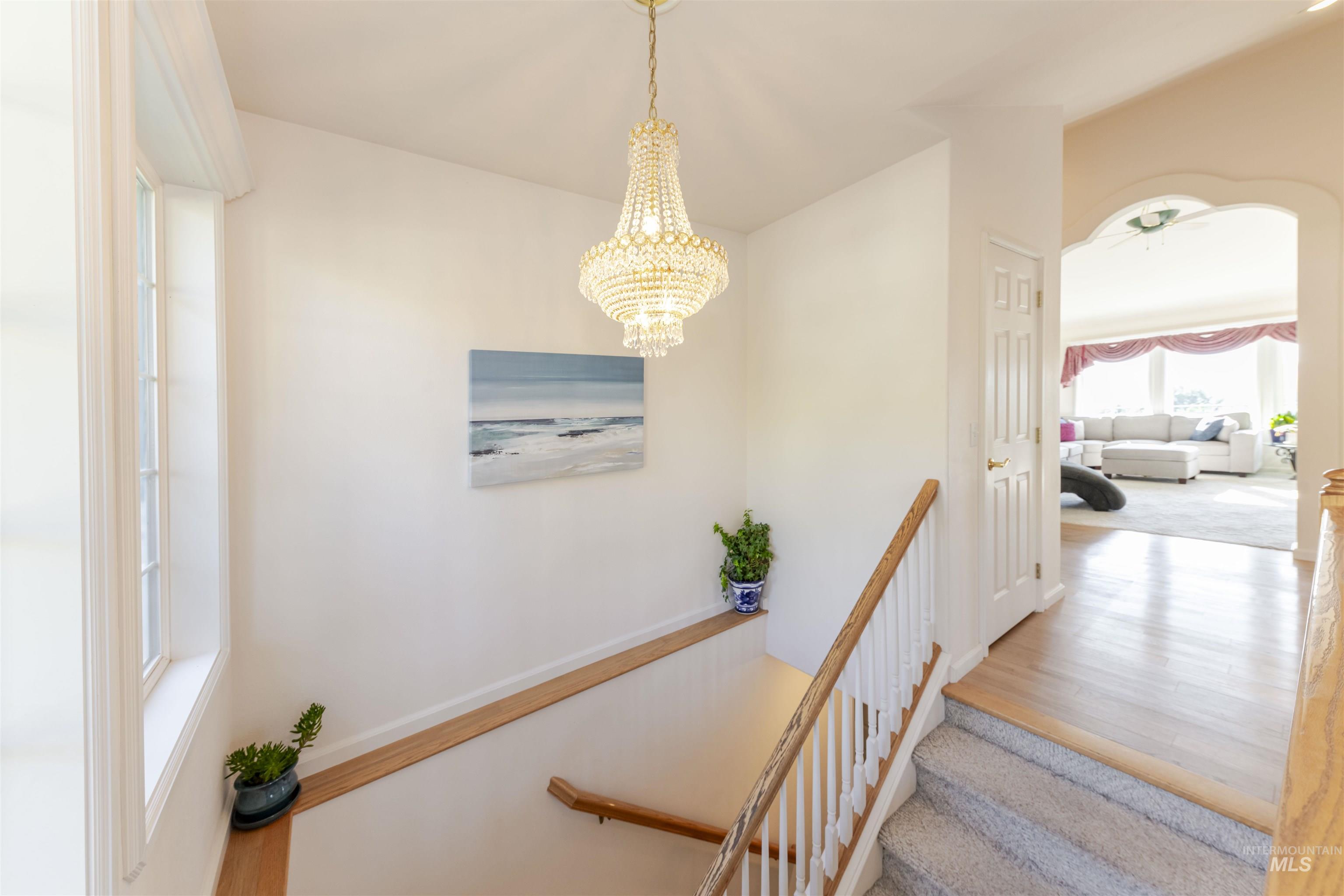 Stairway with a chandelier, wood finished floors, and a ceiling fan
