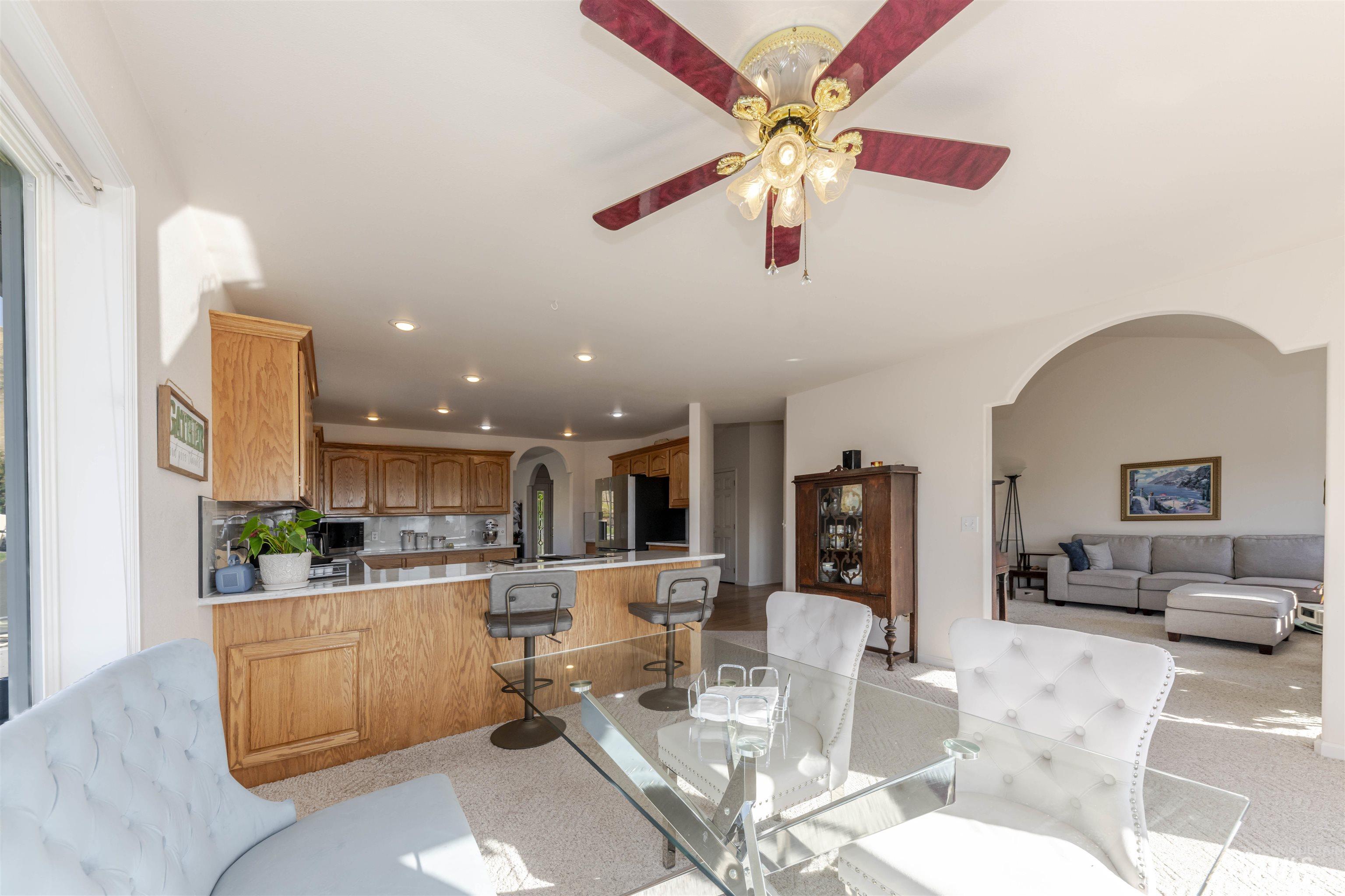 Dining space with arched walkways, light colored carpet, recessed lighting, and a ceiling fan