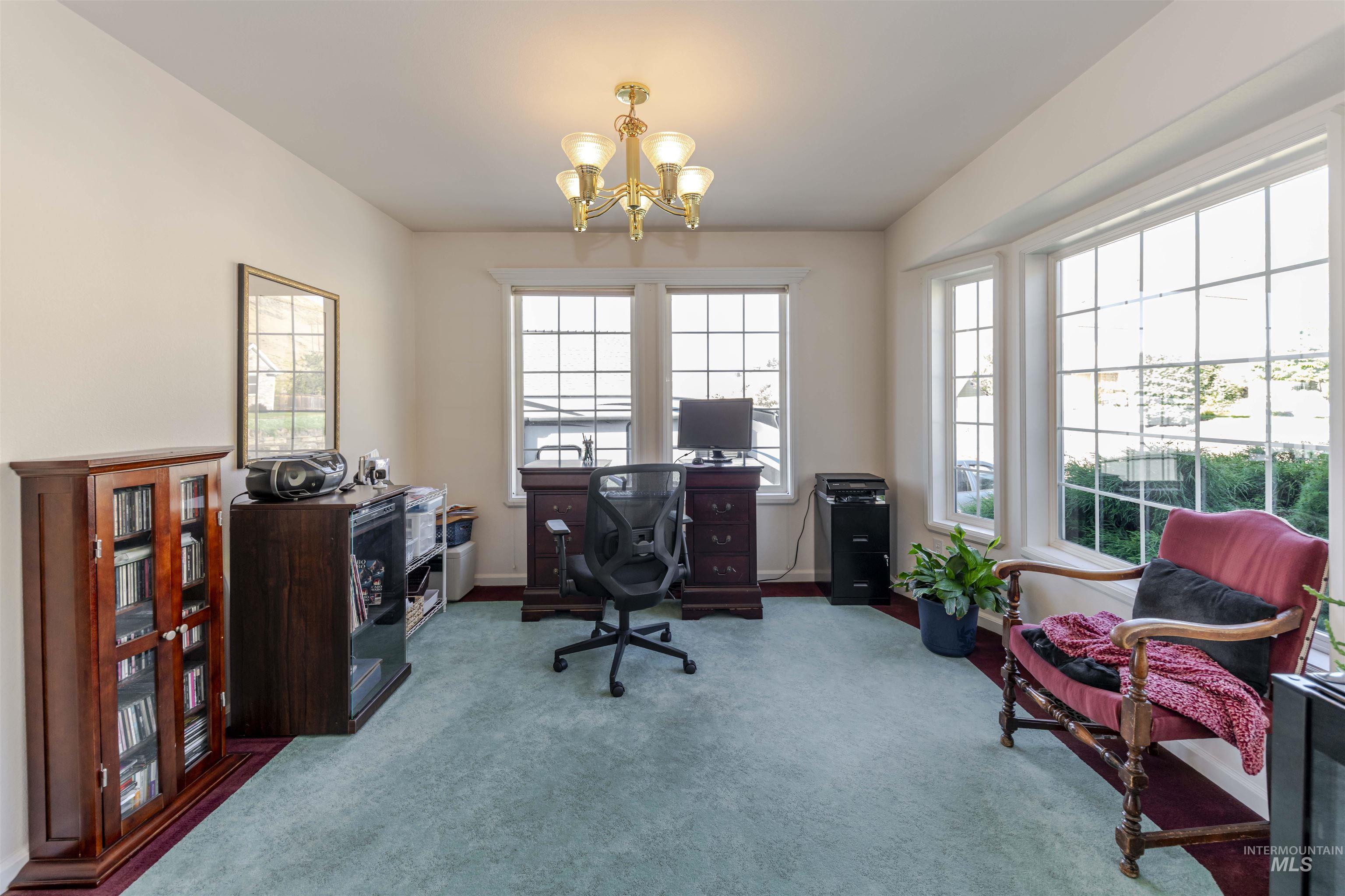 Home office featuring a chandelier and carpet