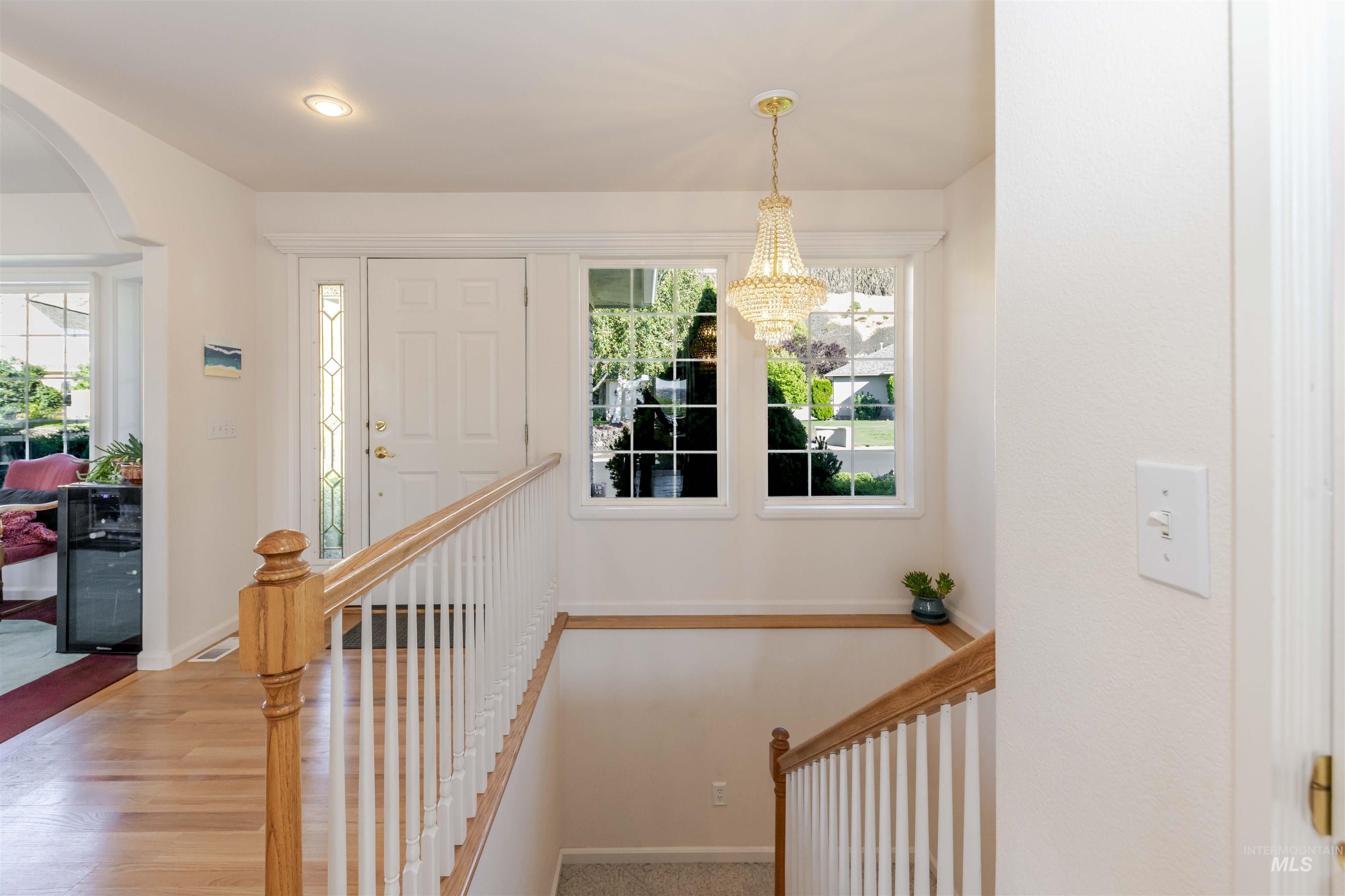 Stairs featuring arched walkways, healthy amount of natural light, and wood finished floors