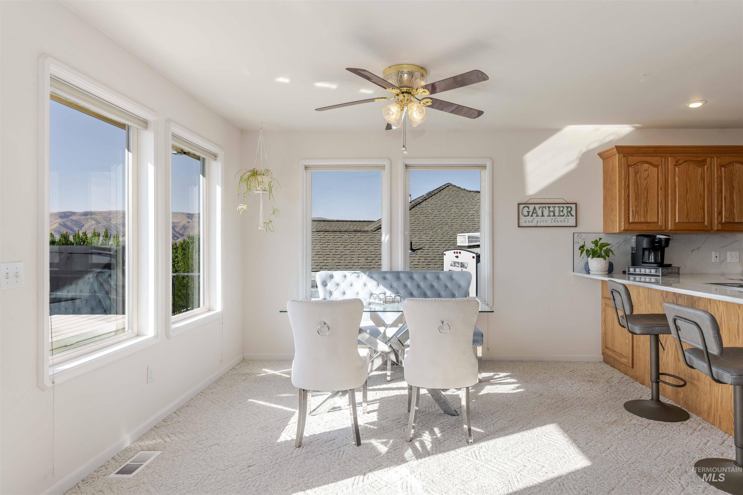 Dining room with light colored carpet and a ceiling fan