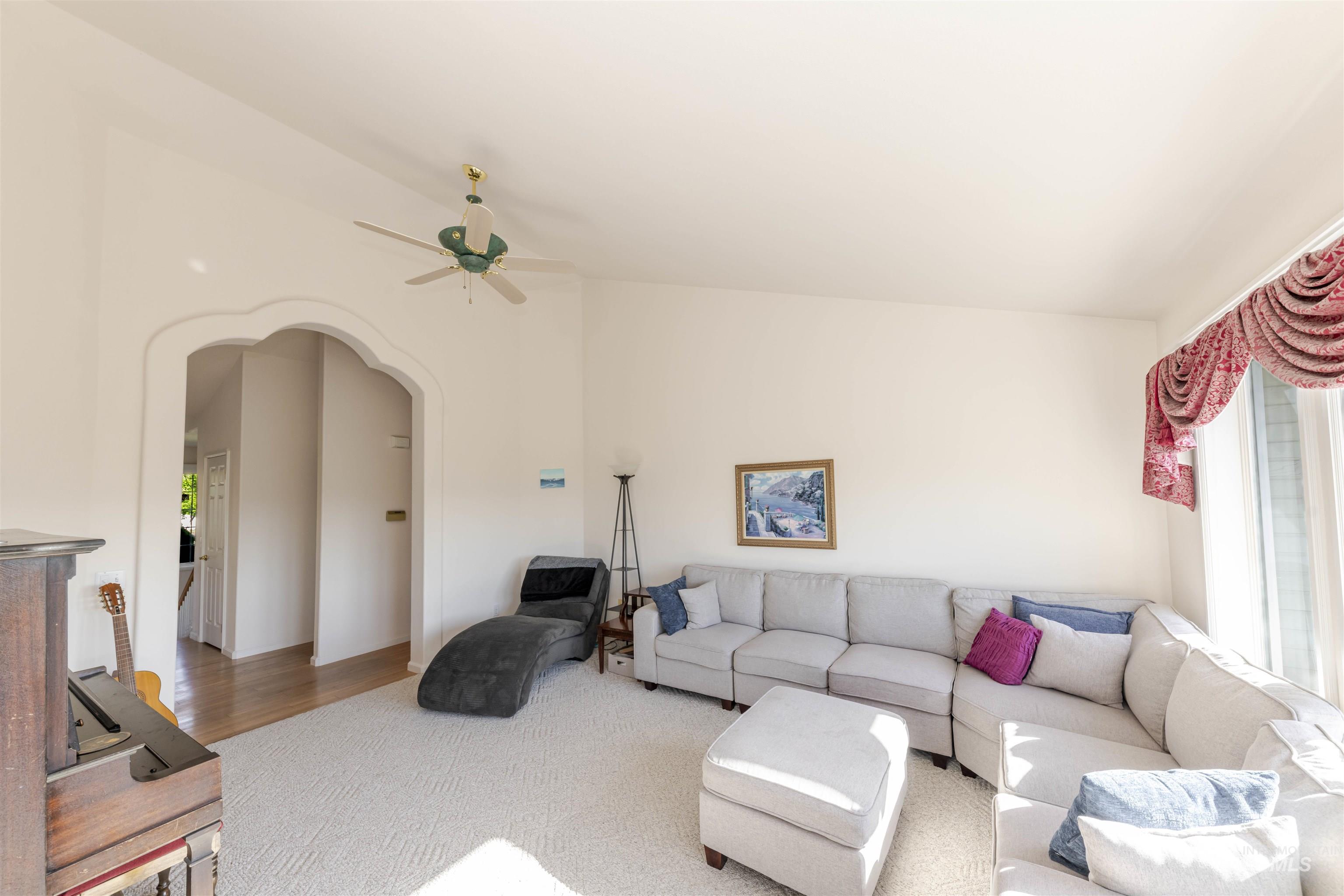 Living area featuring arched walkways, plenty of natural light, and a ceiling fan
