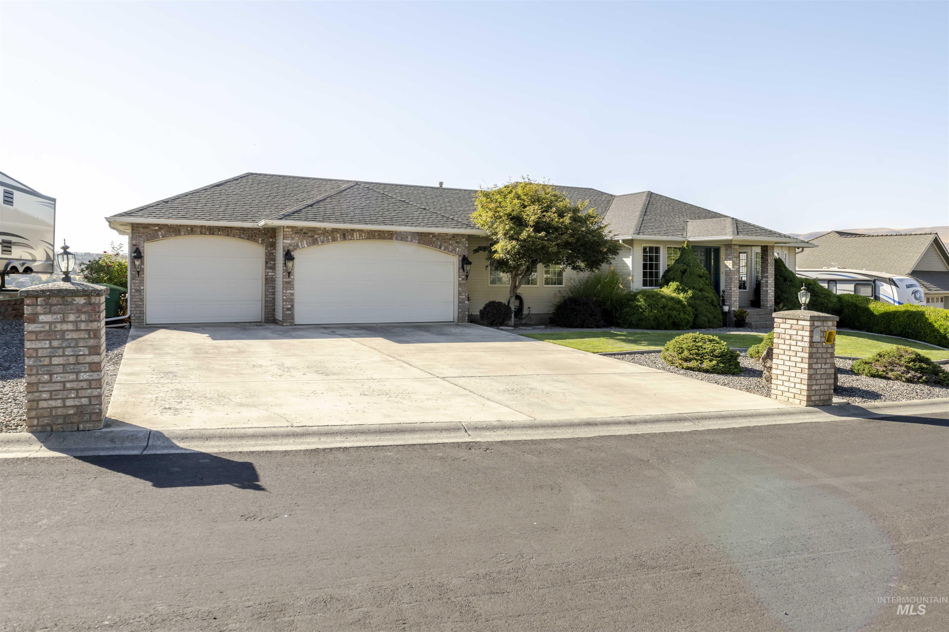 Single story home with roof with shingles, concrete driveway, an attached garage, and brick siding